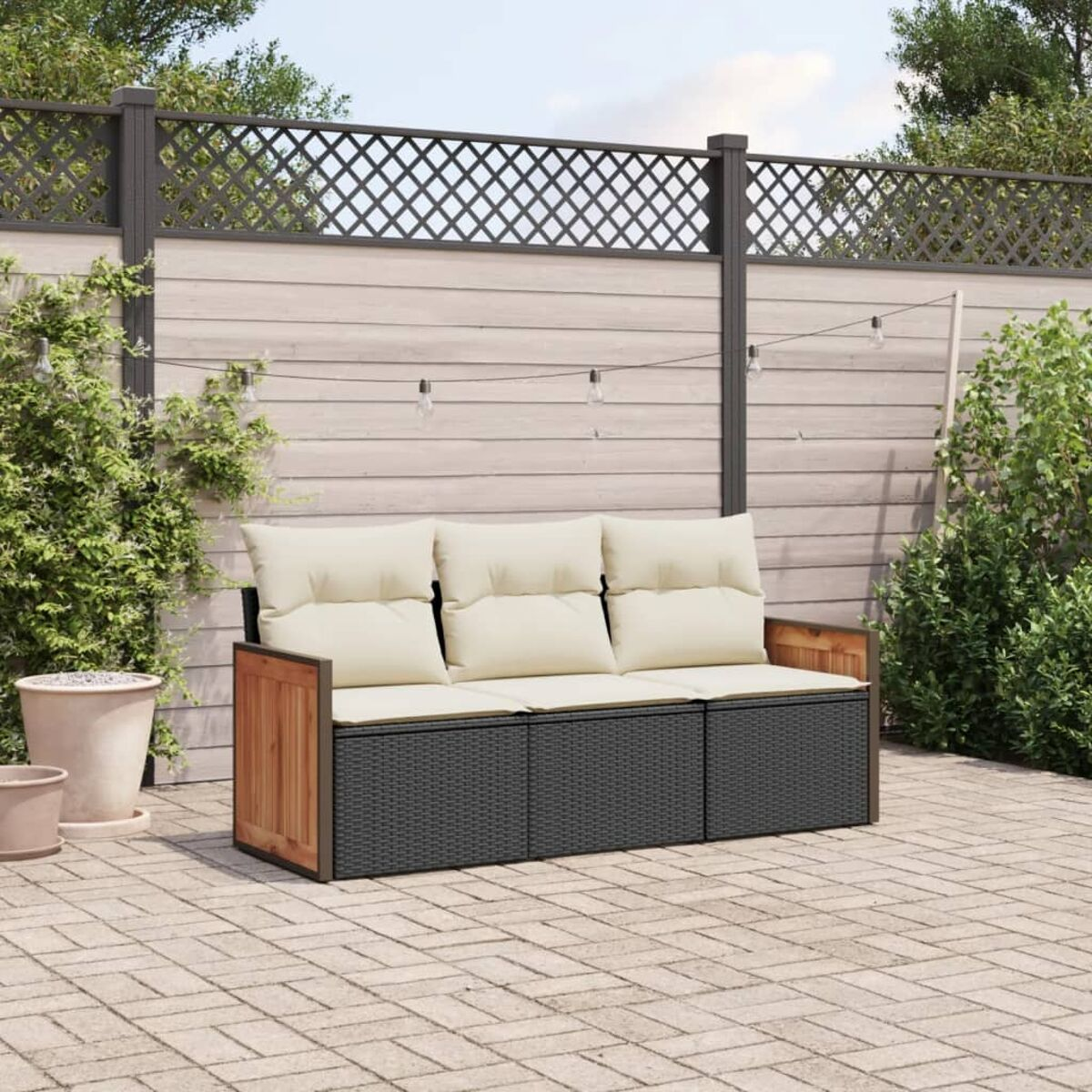 Dreisitziges Sofa mit cremefarbenen Kissen, schwarzem Webrahmen und Holzseiten, auf Terrasse mit Zaun.
