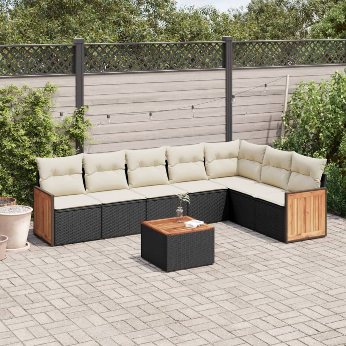 Ecksofa im Freien mit cremefarbenen Kissen, schwarzem Korbgeflecht und einem Holztisch auf einer Terrasse.