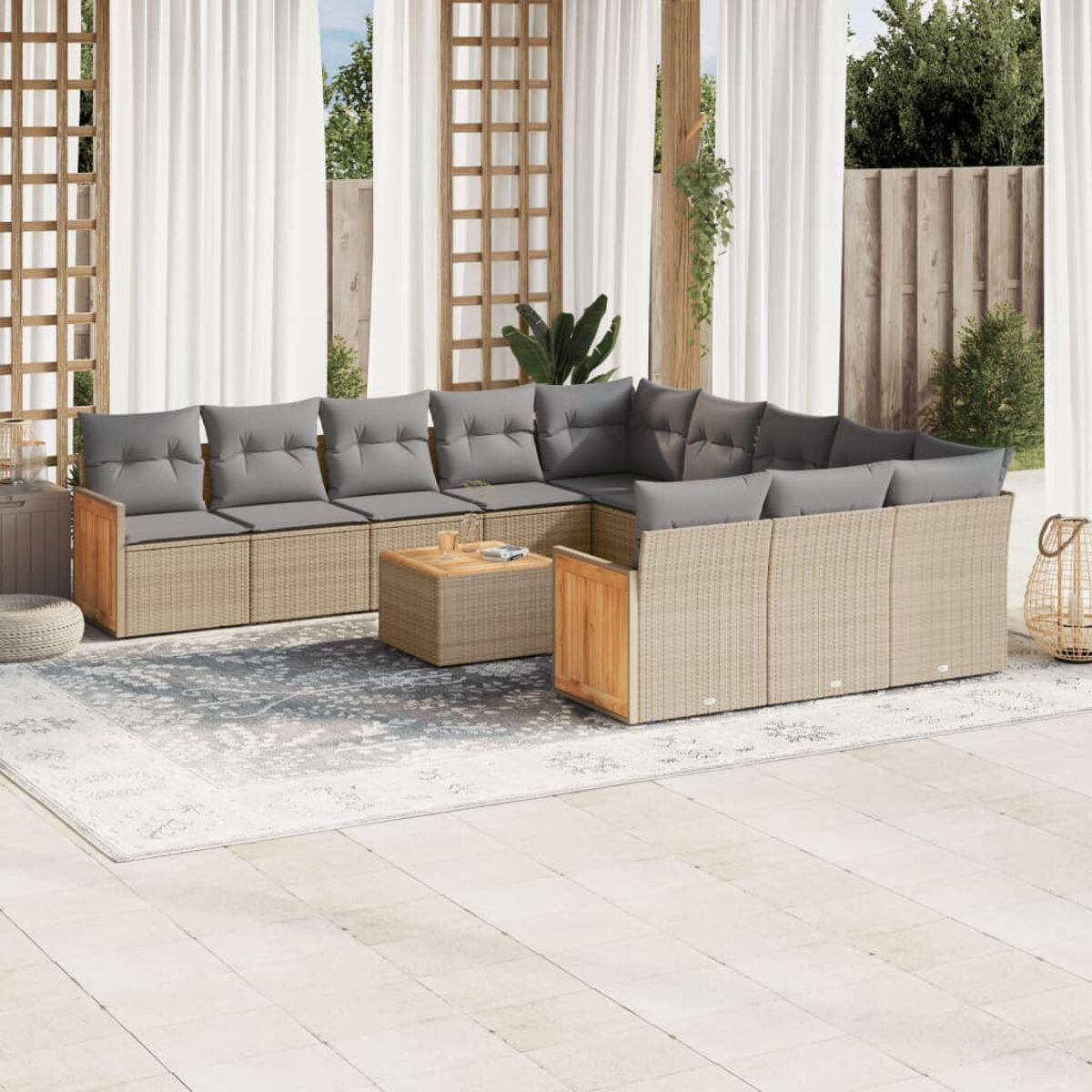 Outdoor-Set: graue Kissen auf Korbsessel und Couchtisch. Weiße Vorhänge und Pflanzen im Hintergrund.