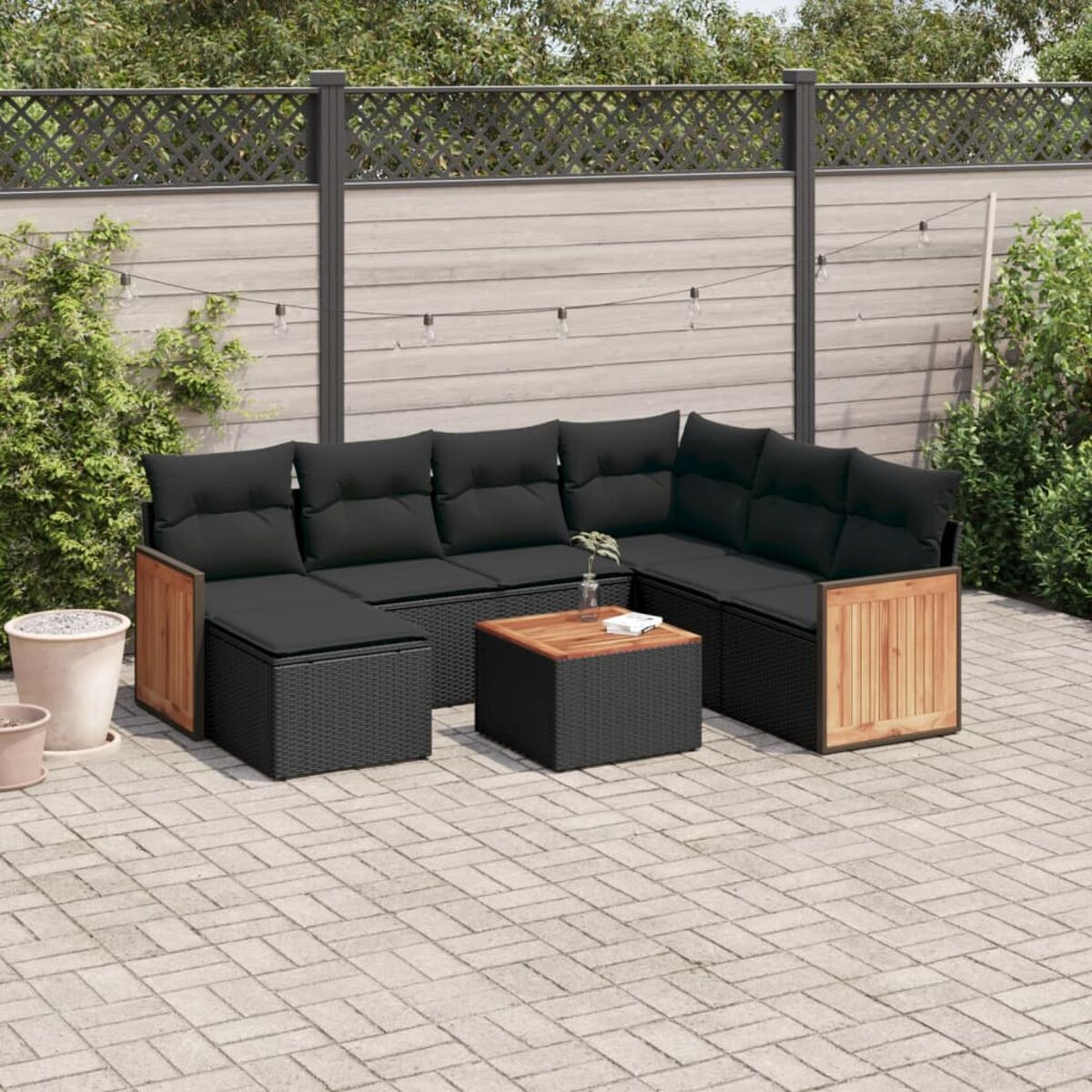 Schwarzes Ecksofa aus Korbgeflecht für den Außenbereich mit schwarzen Kissen, Couchtisch und Holzseitenteilen.