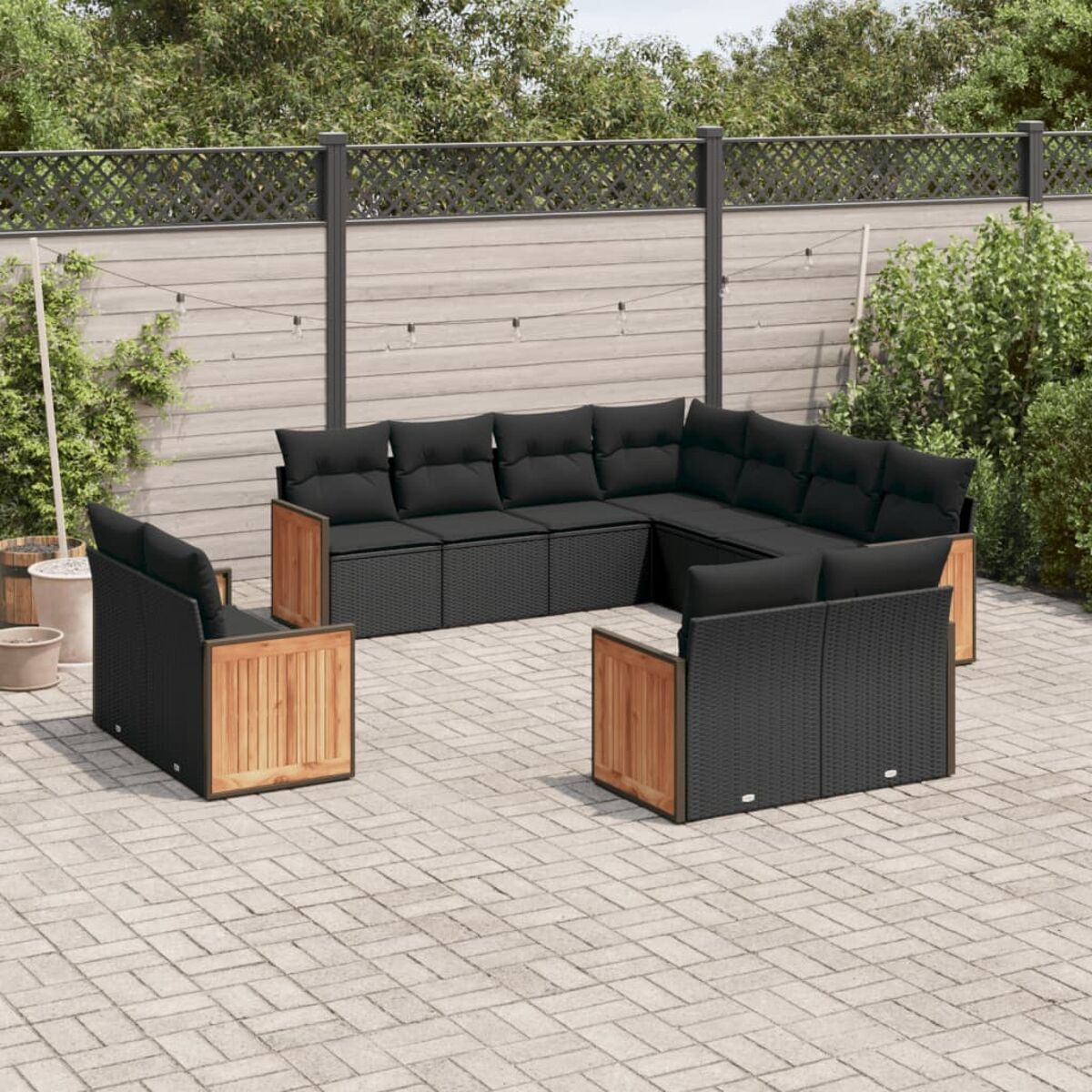 Schwarzes Rattansofa-Set mit schwarzen Kissen und Holzakzenten. Auf einer Terrasse.