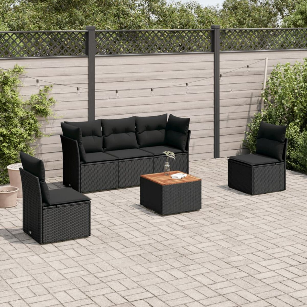 Schwarzes Outdoor-Geflecht-Sitzensemble auf Backstein-Terrasse.
