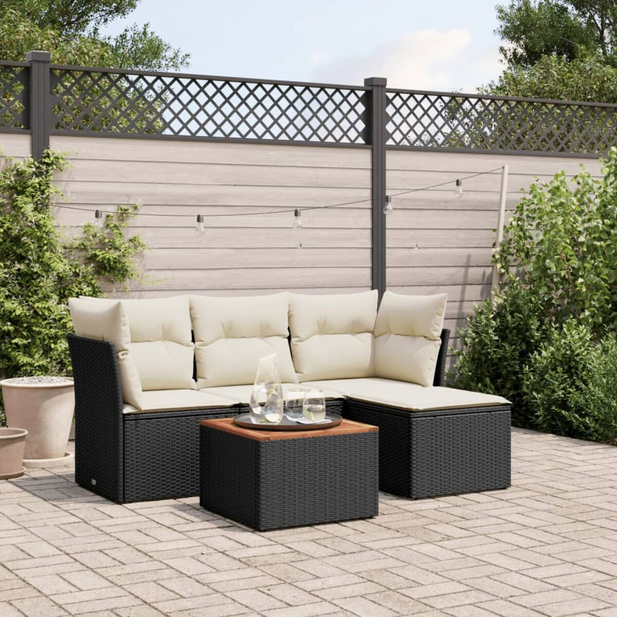 Schwarzes Outdoor-Ecksofa mit beigen Kissen und Tisch auf Backstein-Terrasse.