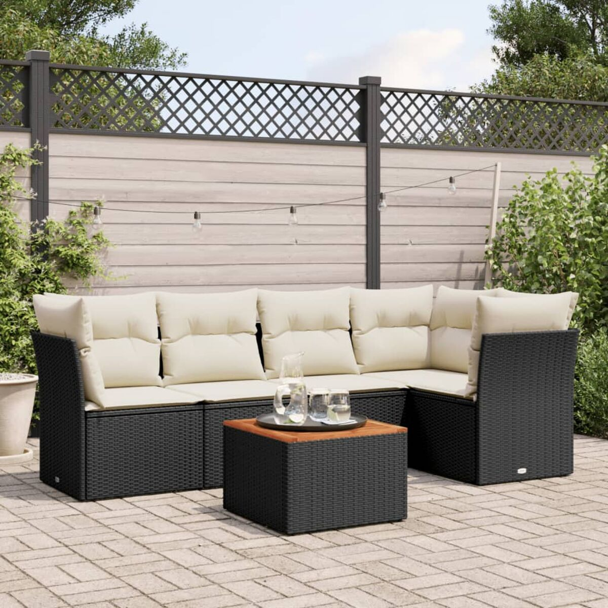 Schwarzes Outdoor-Ecksofa mit cremefarbenen Kissen und Holztisch.