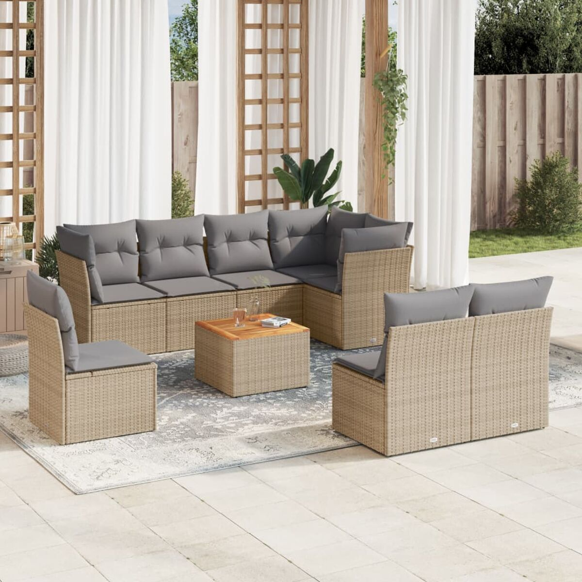 Terrassenset mit hellen Korbmöbeln, grauen Kissen, einem Couchtisch und einem Teppich auf einer Terrasse.