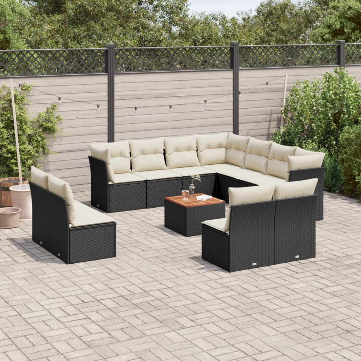 Schwarzes Rattan-Gartenmöbel-Set mit cremefarbenen Kissen.
