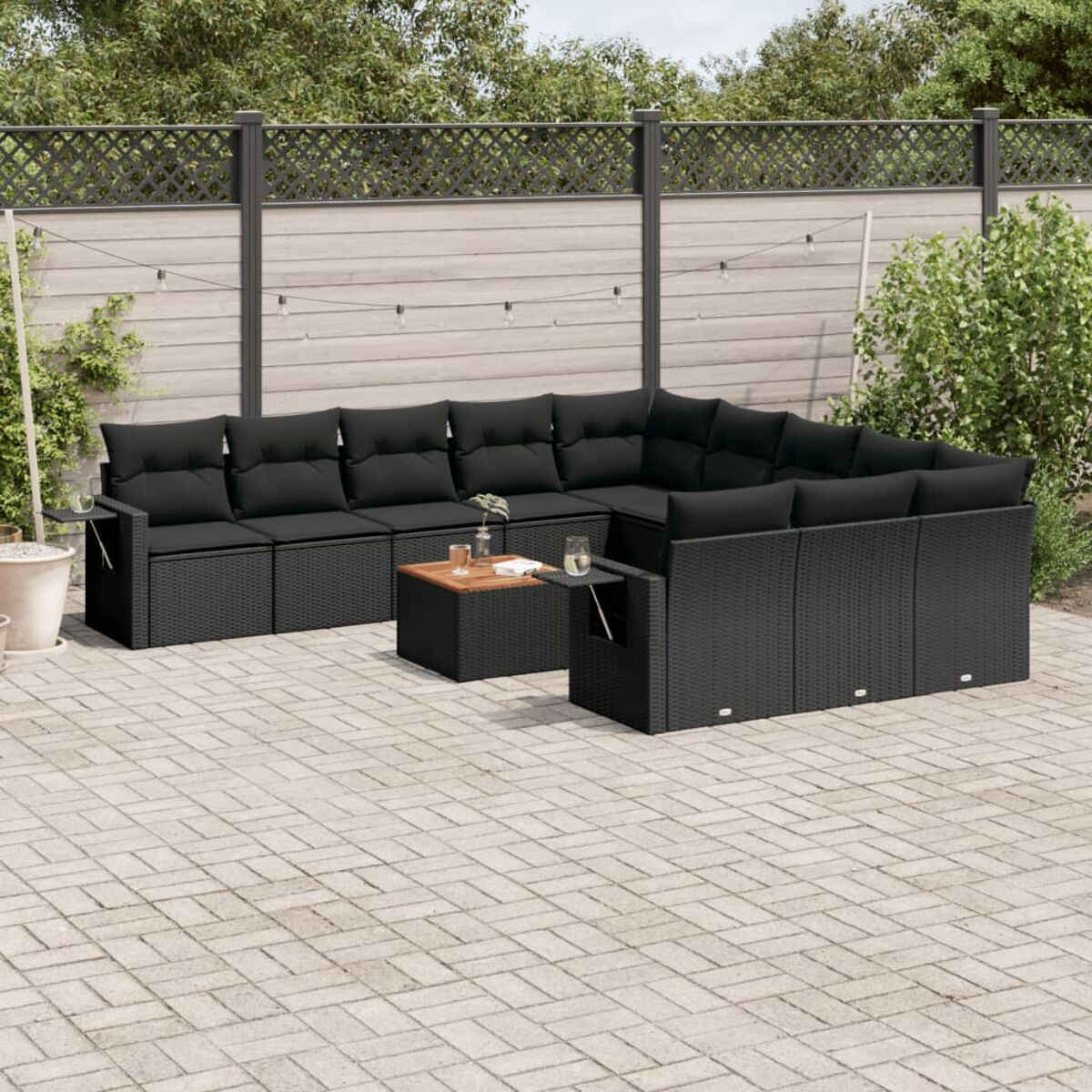 Schwarzes Ecksofa aus Korbgeflecht für den Außenbereich mit schwarzen Kissen, Couchtisch und Beistelltischen.