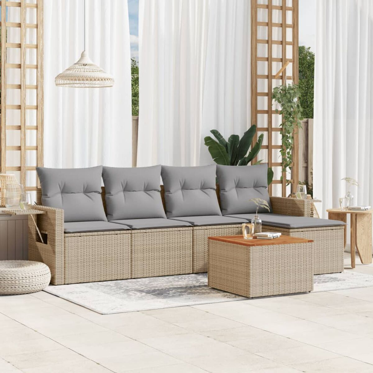 Outdoor-Rattansofa-Set mit grauen Kissen, Couchtisch und Teppich auf einer Terrasse, mit Vorhängen.