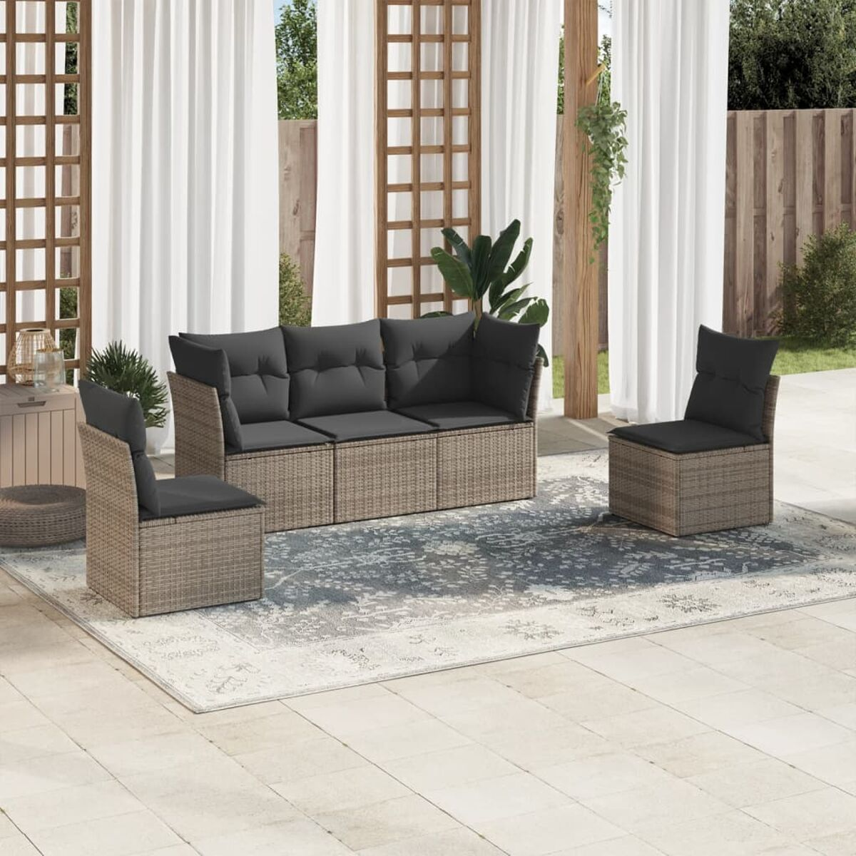 Rattansofa und Stühle mit grauen Kissen auf einem gemusterten Teppich, mit einem Terrassenhintergrund.