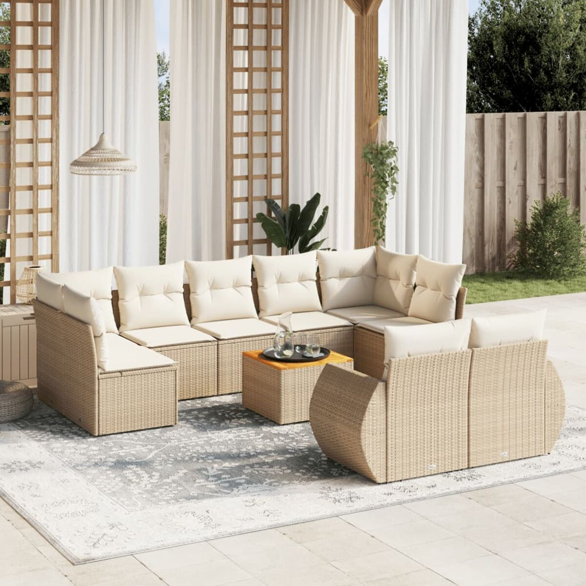 Outdoor-Sofa aus hellbraunem Korbgeflecht mit cremefarbenen Kissen, einem Couchtisch und weißen Vorhängen.