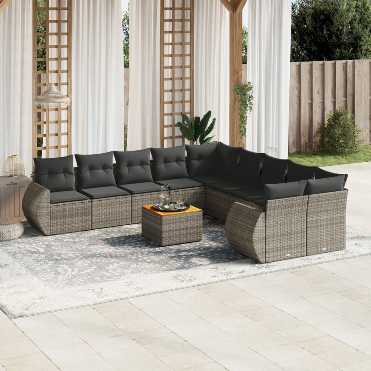 Outdoor-Ecksofa mit dunklen Kissen, kleinem Tisch und hellem Teppich auf einer Terrasse.