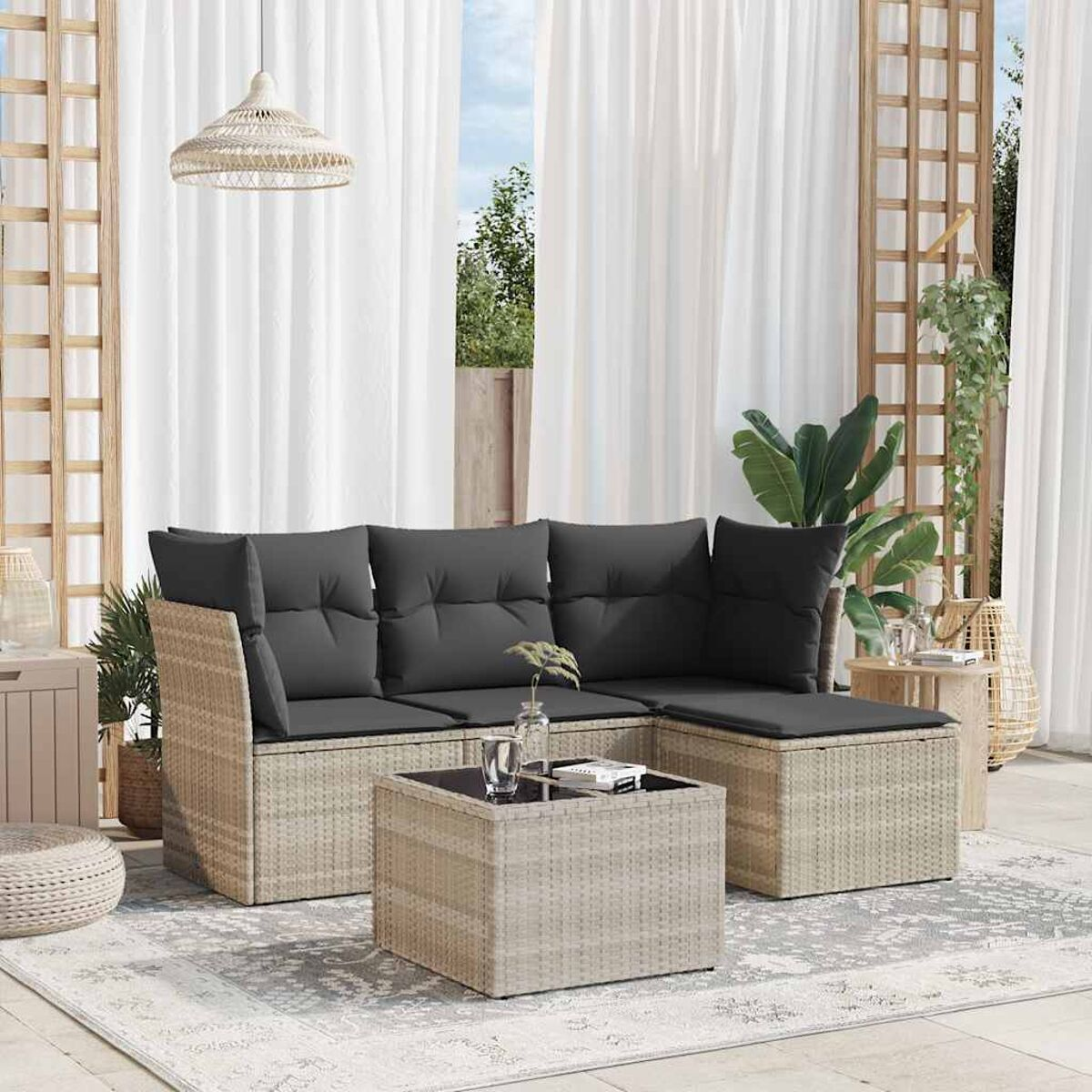 Beiges Outdoor-Geflecht-Ecksofa mit grauen Kissen, Couchtisch und weißen Vorhängen im Hintergrund.