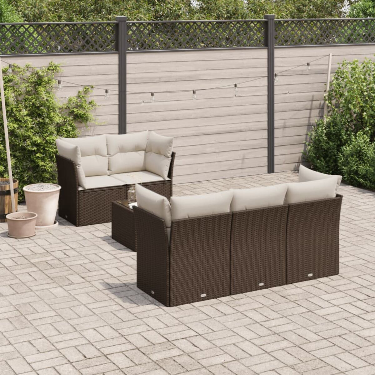 Mobili da esterno in vimini marrone con cuscini beige. Su un patio.