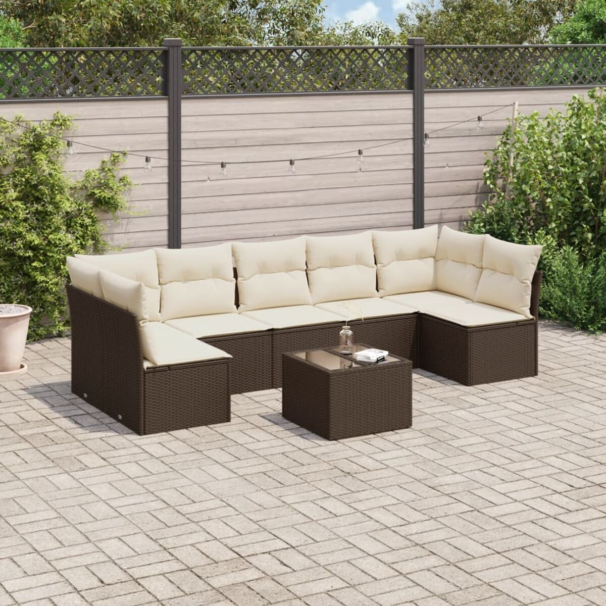 Braunes Rattan-Sofaset mit cremefarbenen Kissen und einem Tisch mit Glasplatte.