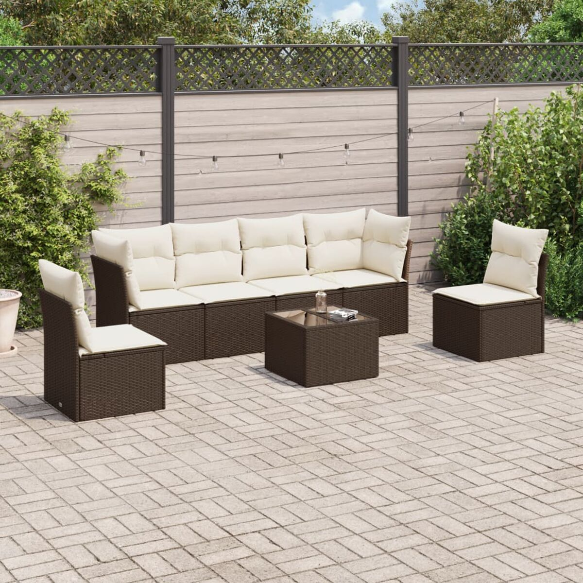 Set da patio marrone con cuscini color crema su un patio con un tavolo quadrato marrone.
