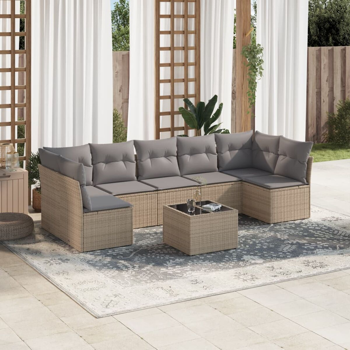 Szene im Freien: Korbmöbel-Set mit grauen Kissen, Couchtisch und weißen Vorhängen.