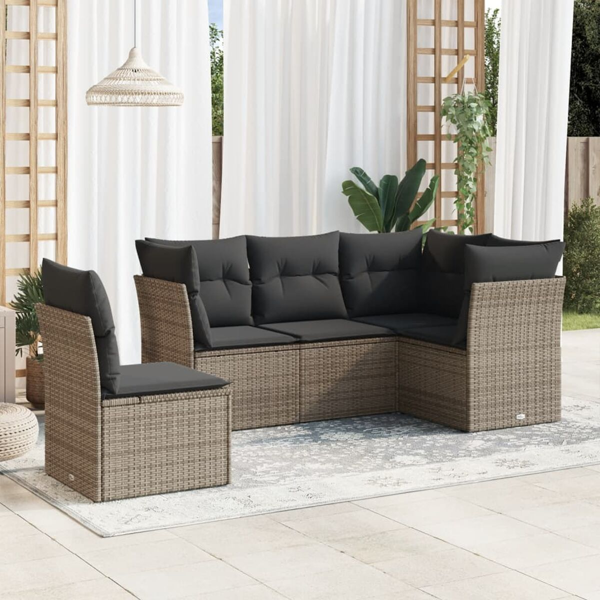 Wicker-Gartenmöbelset mit grauen Kissen, einem Stuhl und Pflanzen auf einem gemusterten Teppich.