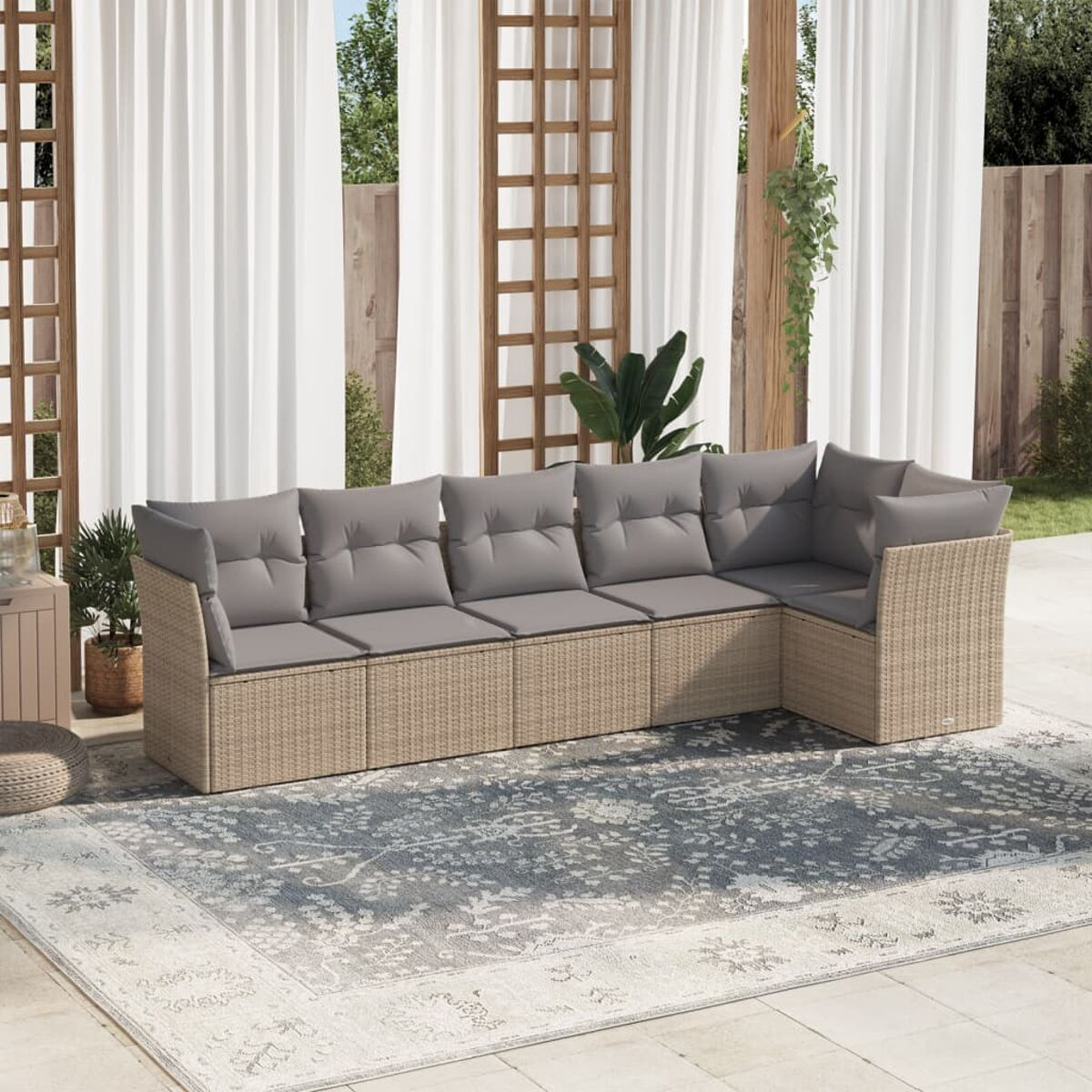 Rattan-Ecksofa für den Außenbereich mit grauen Kissen, einem Teppich und einem Spalier.