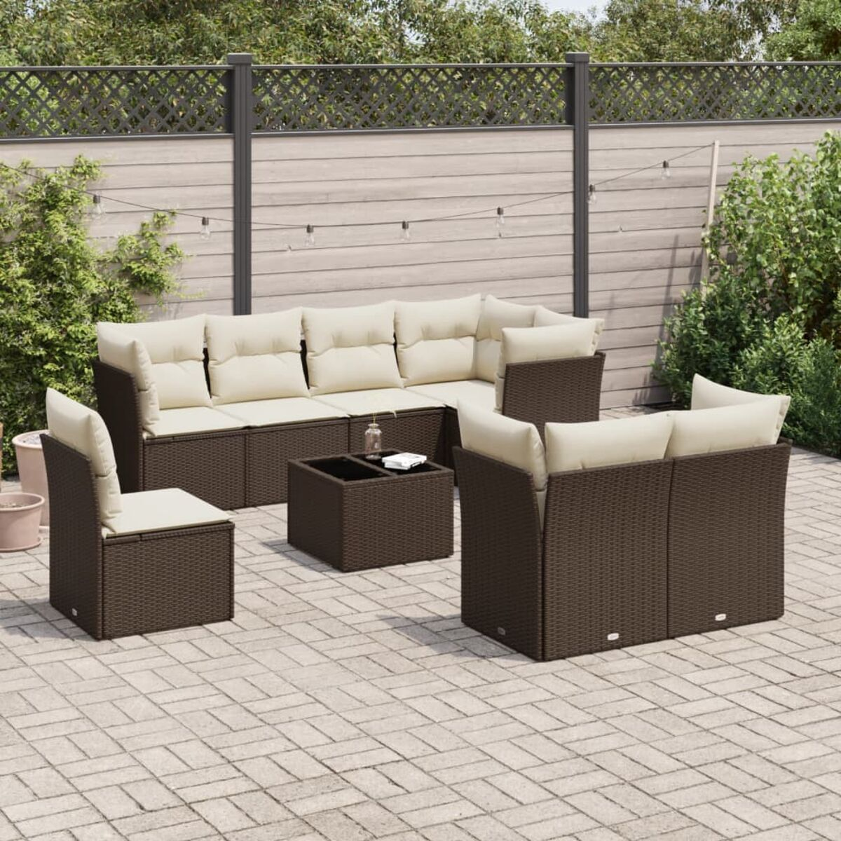 Outdoor-Sofa aus braunem Korbgeflecht mit cremefarbenen Kissen und quadratischem Couchtisch auf Terrasse.