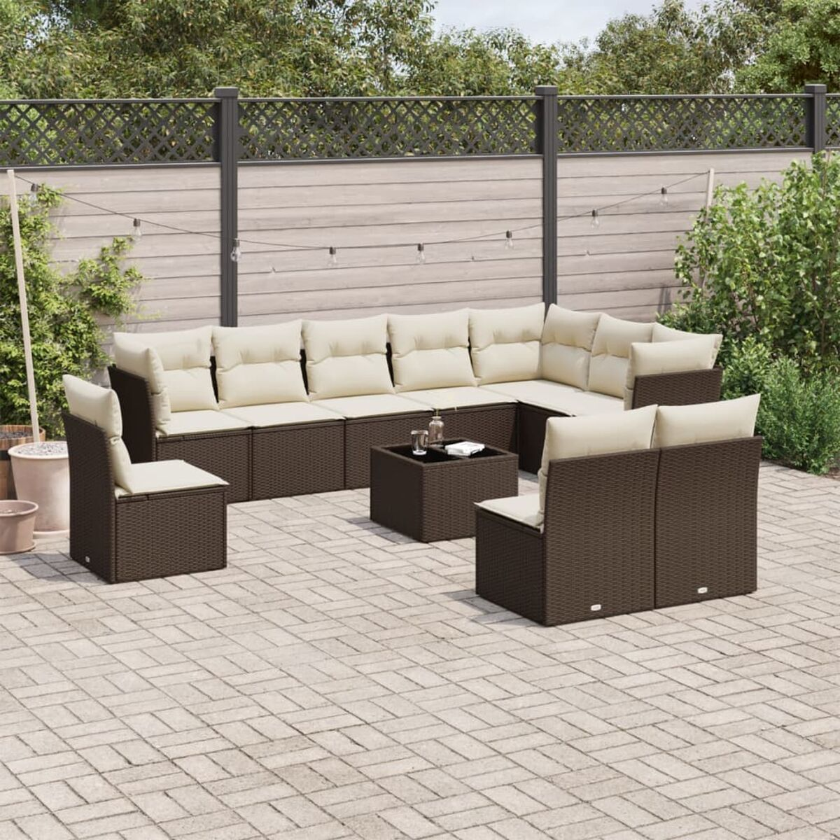 Un set da patio con un divano in rattan marrone scuro, cuscini beige e un tavolino su un patio.
