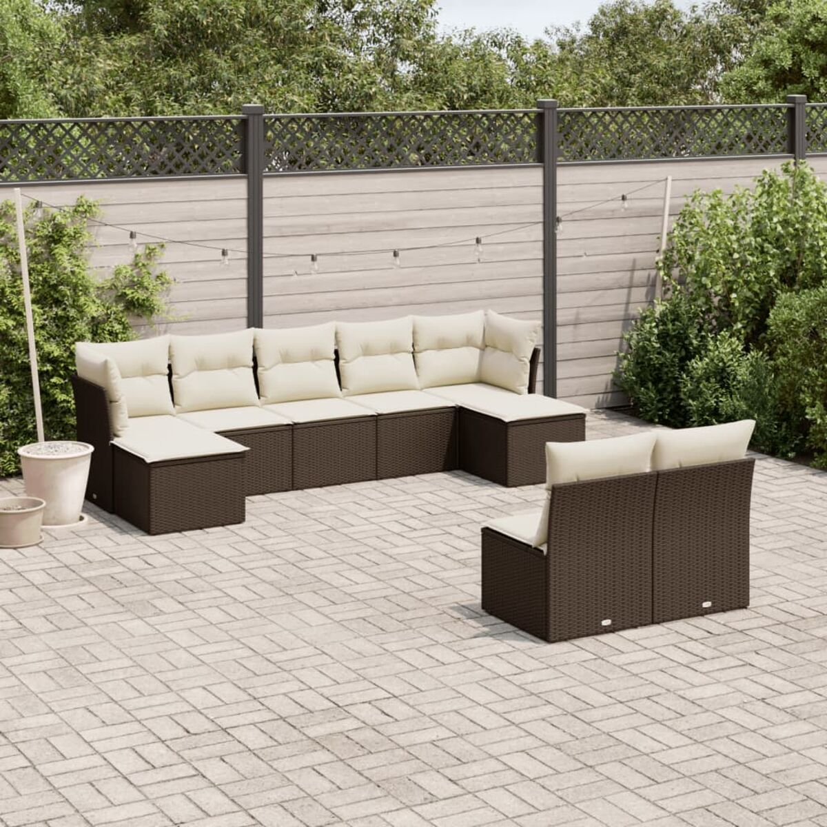 Braunes Outdoor-Ecksofa aus Korbgeflecht mit cremefarbenen Kissen, Stuhl und Ziegelpflasterung.