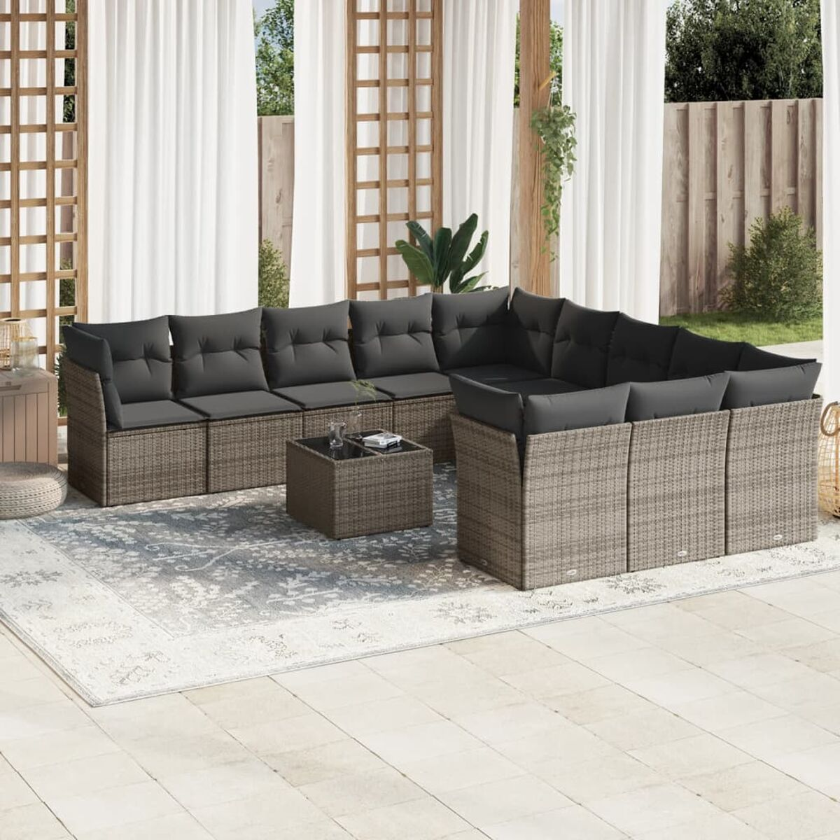 Rattan-Ecksofa für den Außenbereich mit dunkelgrauen Kissen und Couchtisch auf einer Terrasse.