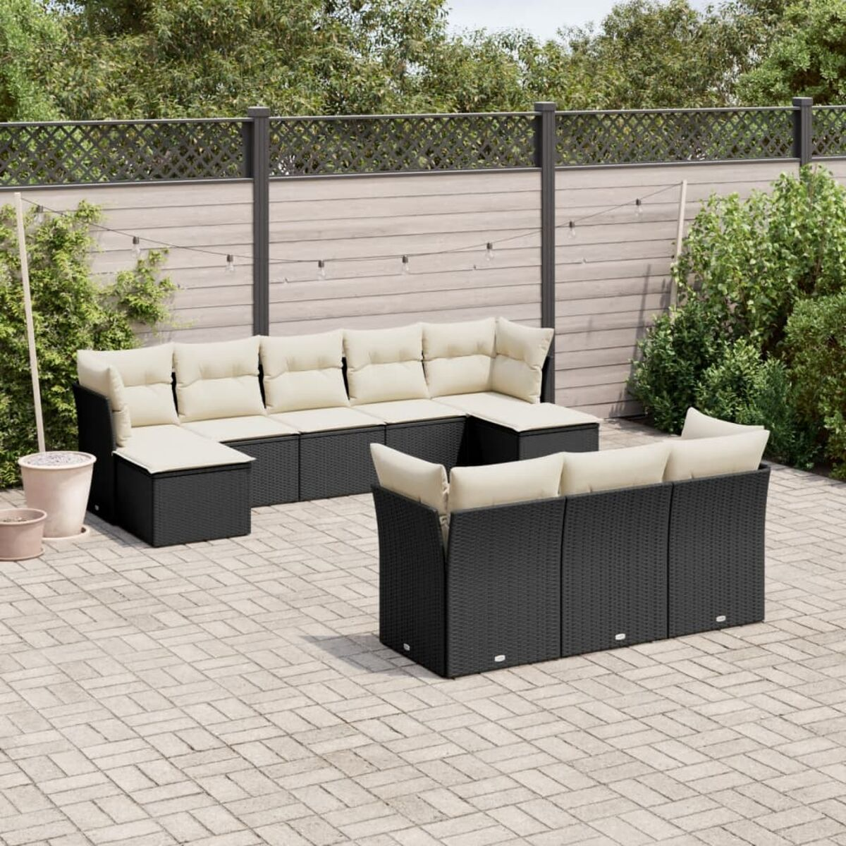 Schwarzes Outdoor-Ecksofa aus Korbgeflecht mit cremefarbenen Kissen. Auf Ziegel-Terrasse.