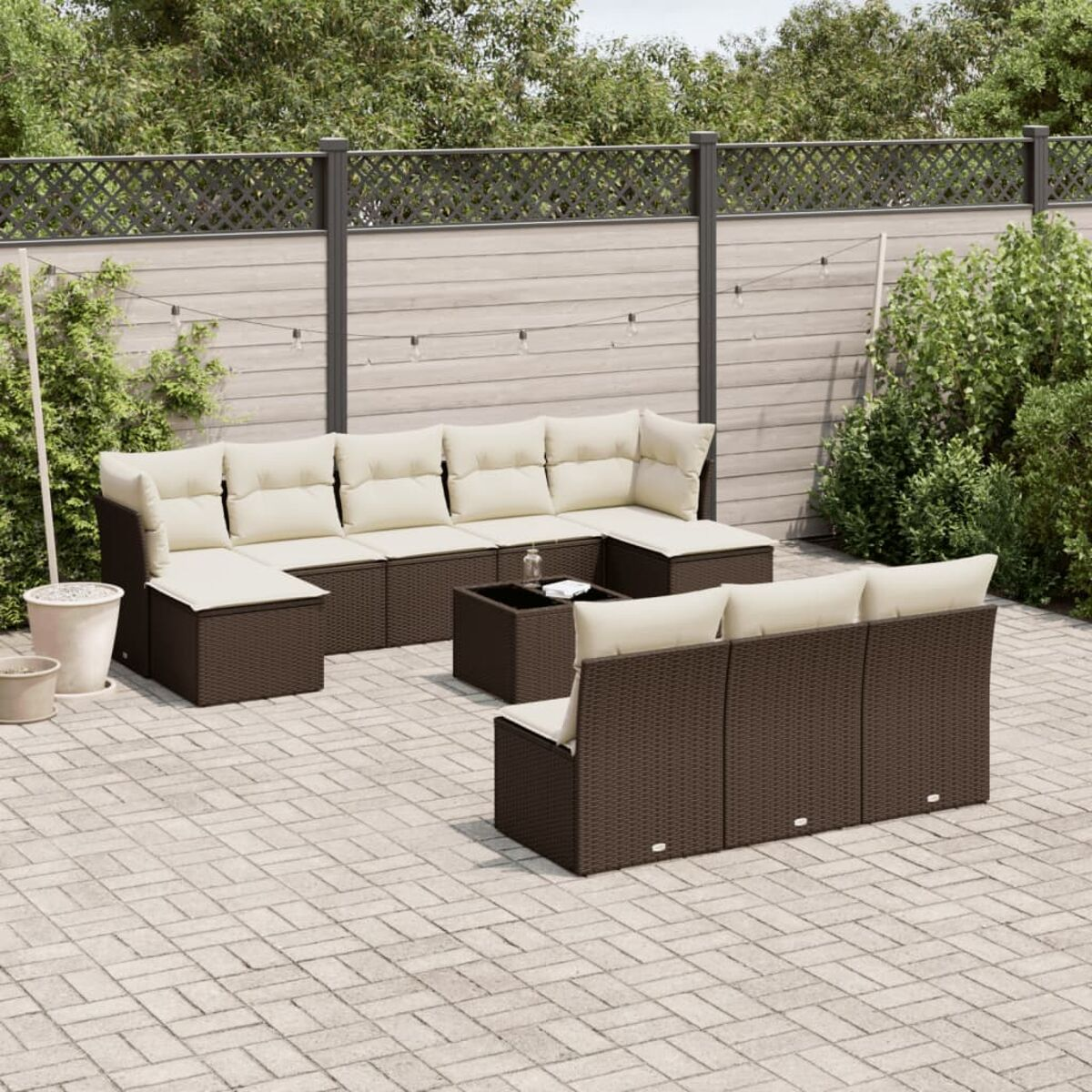 Set divano componibile in vimini marrone con cuscini beige su un patio.