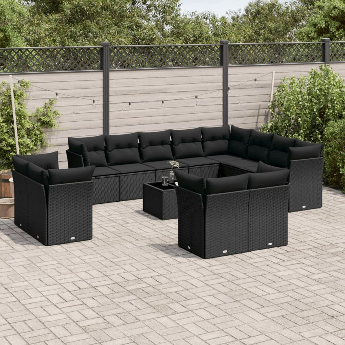 Schwarzes Outdoor-Geflechtmöbel-Set mit schwarzen Kissen auf einer Terrasse. Enthält einen Tisch und Sitzgelegenheiten.