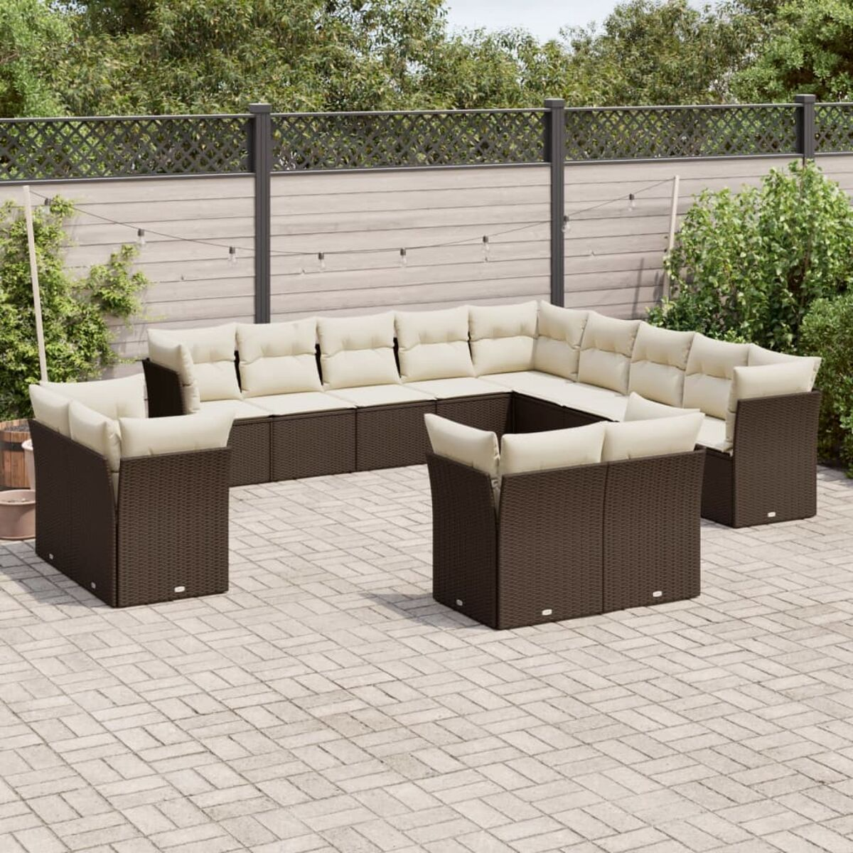 Braunes Rattansofa-Set mit beigen Kissen. Auf einer Terrasse mit grauen Pflastersteinen.