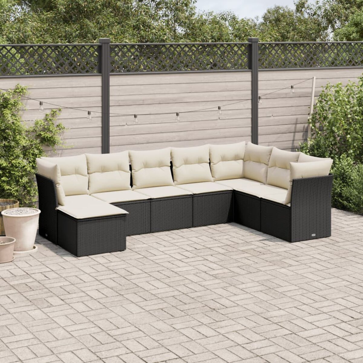 L-förmiges Terrassenset mit schwarzen gewebten Möbeln, beigen Kissen und einer Backsteinterrasse im Hintergrund.