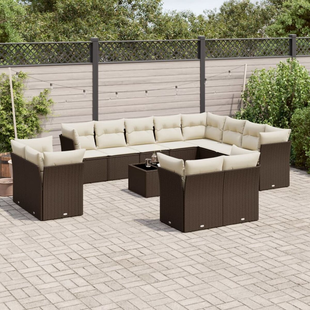 Divano componibile in rattan con cuscini color crema e tavolino su un patio.
