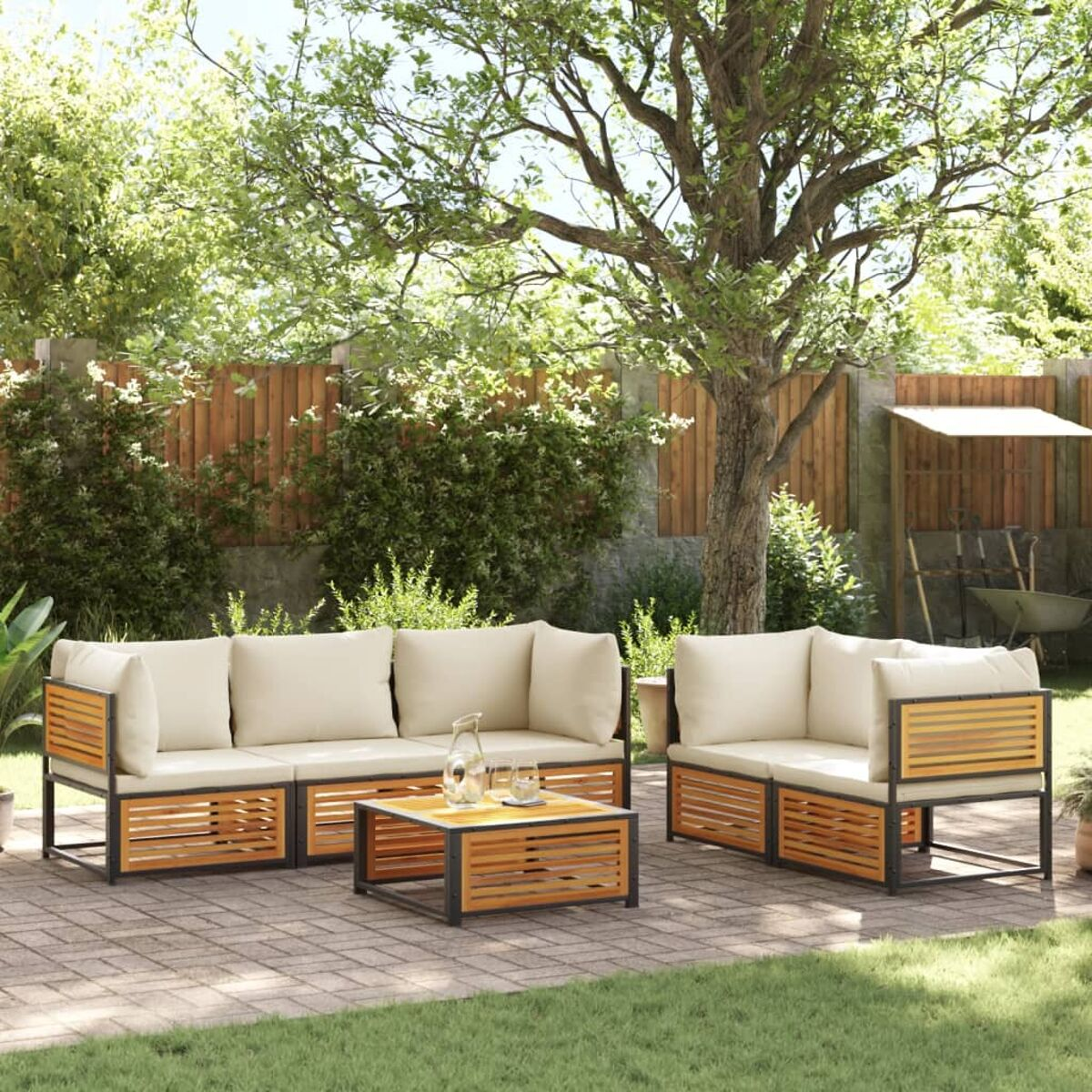 Outdoor-Sofa-Set mit Holzrahmen, cremefarbenen Kissen und einem Tisch auf der Terrasse. Bäume im Hintergrund.