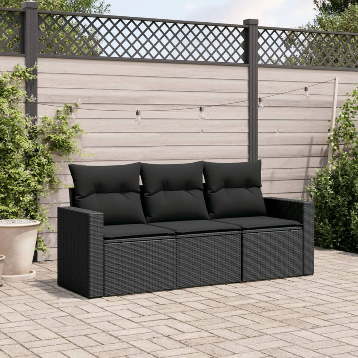 Schwarzes Outdoor-Korbmöbel mit schwarzen Kissen. Auf Ziegel-Terrasse.