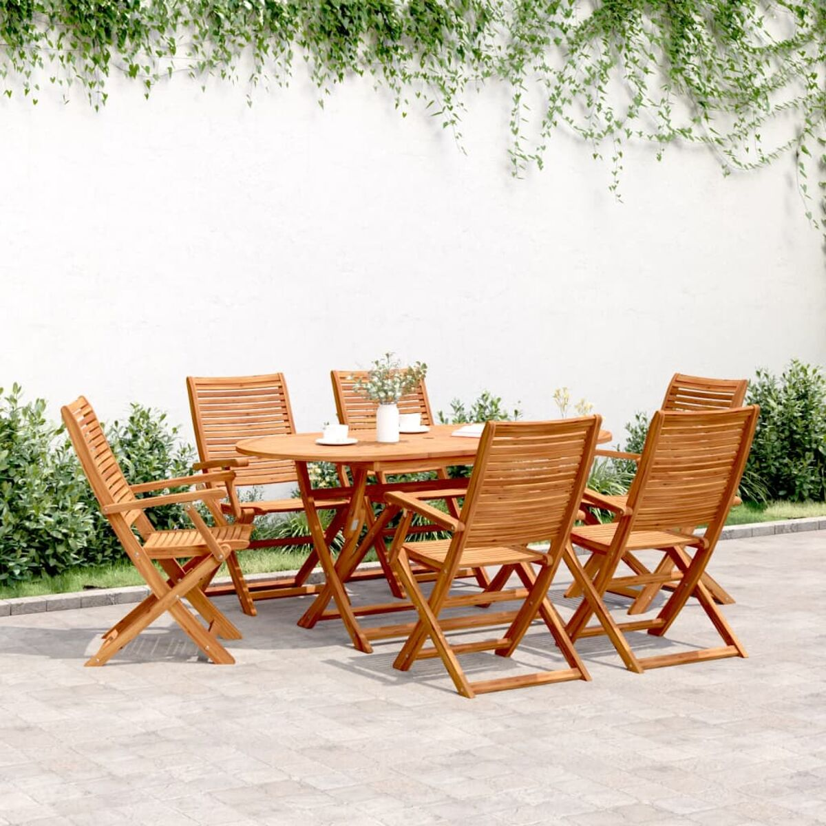 Set da pranzo in legno per esterni con tavolo ovale e sei sedie su un patio in pietra.