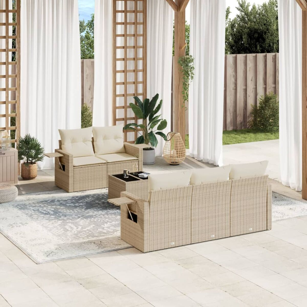Terrassenmöbel-Set im Freien mit beigen Korbmöbeln, Kissen und einem hellgrauen Teppich unter weißen Vorhängen.