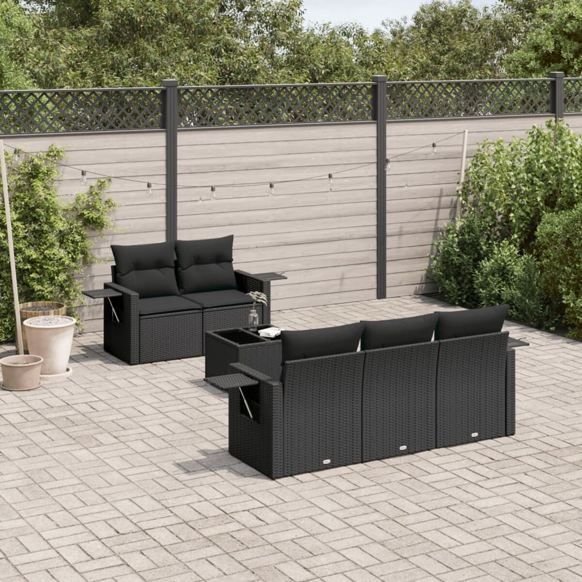 Schwarzes Outdoor-Möbelset aus Korbgeflecht auf einer Backstein-Terrasse.