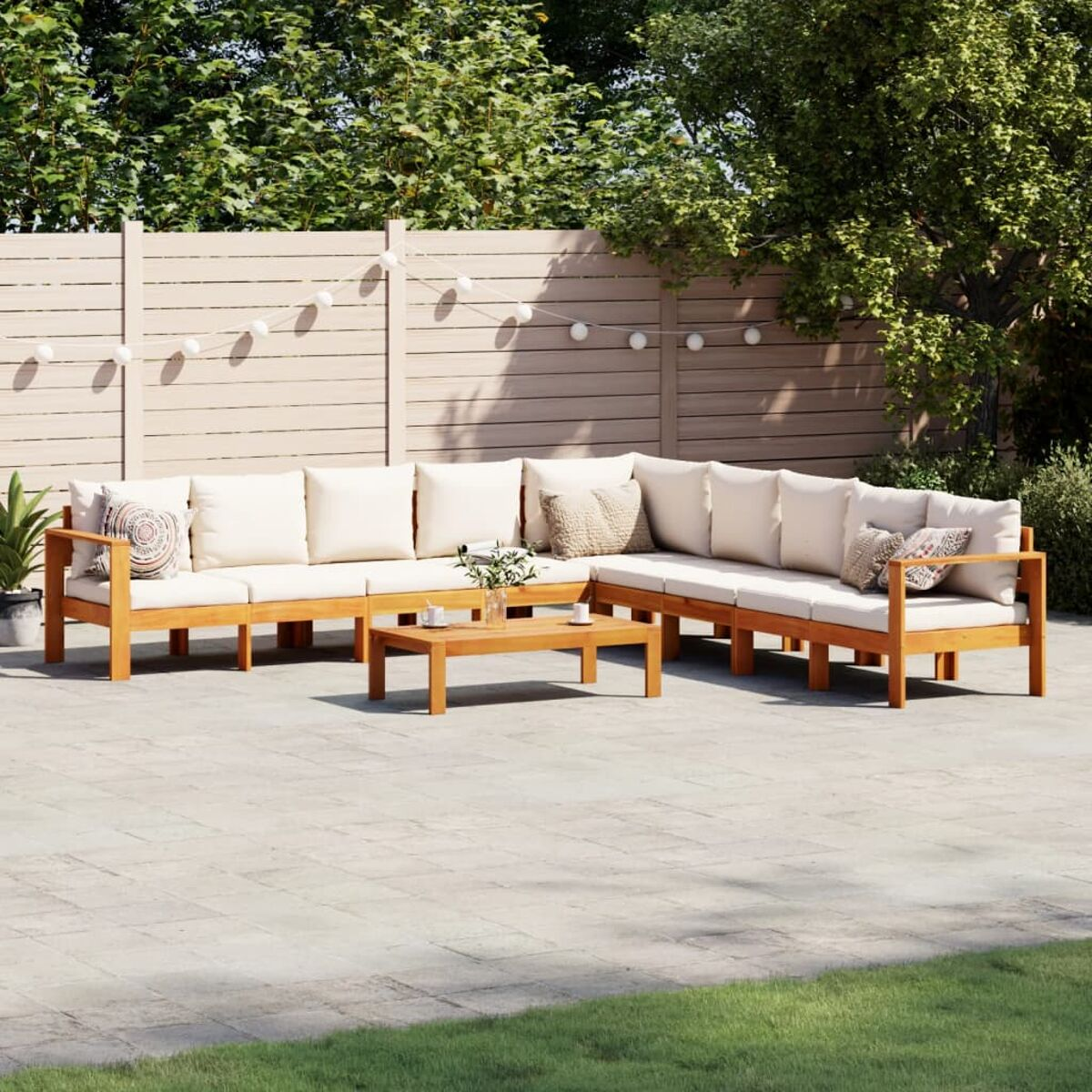 Outdoor-Ecksofa aus Holz mit cremefarbenen Kissen und passendem Couchtisch im Garten.