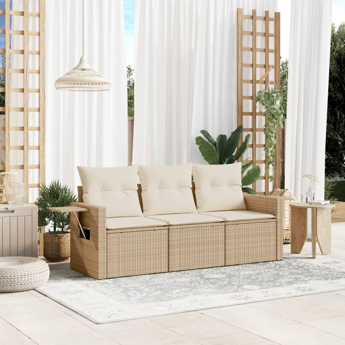 Geflochtenes Outdoor-Sofaset mit cremefarbenen Kissen und einem grauen Teppich. Holzelemente und Pflanzen.