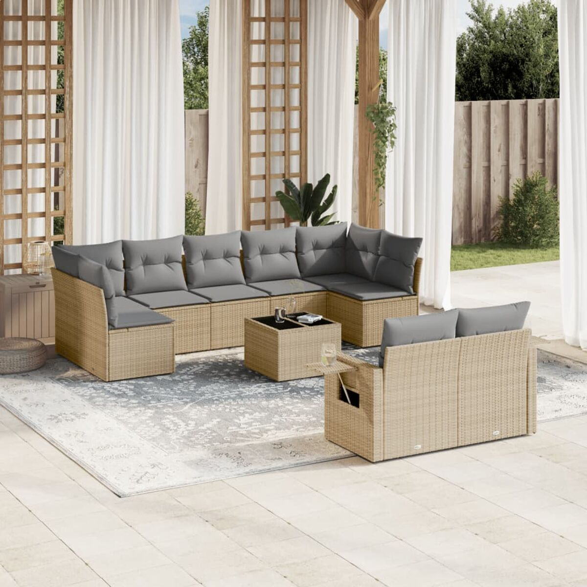 Outdoor-Rattan-Ecksofa, graue Kissen, Couchtisch und Beistelltische. Auf einem Teppich. Vorhänge im Hintergrund.