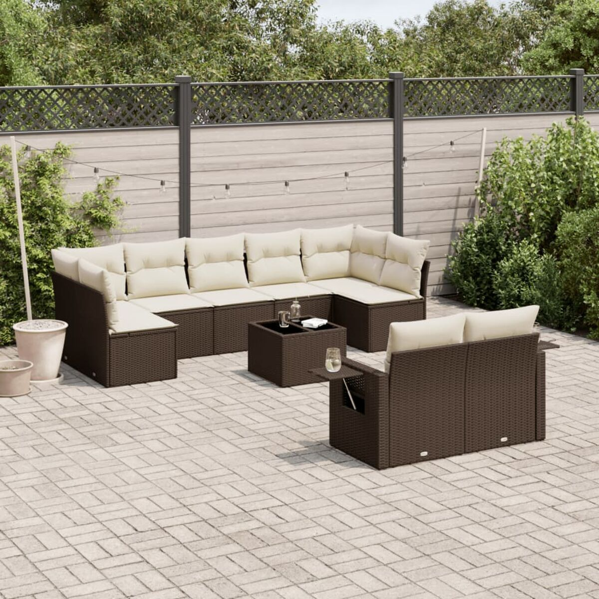 Brauner Korbsessel für den Außenbereich mit cremefarbenen Kissen, Tisch und Beistelltisch. Ziegelterrasse.