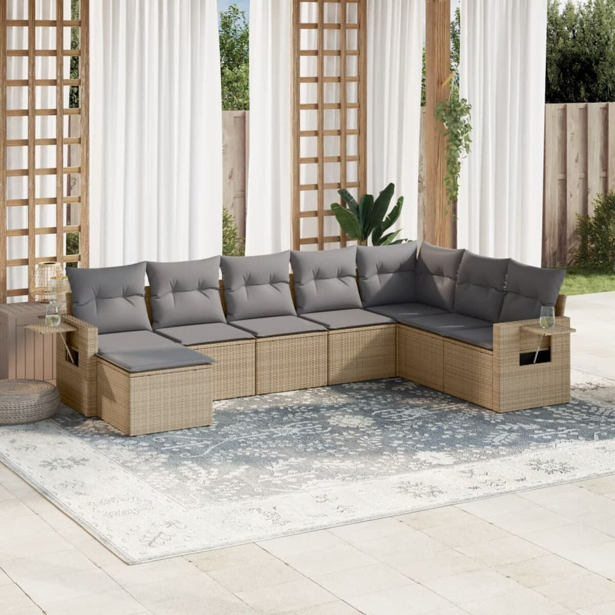 Outdoor-Wicker-Sofagarnitur mit grauen Kissen, auf einem Terrassenteppich, mit Vorhängen.