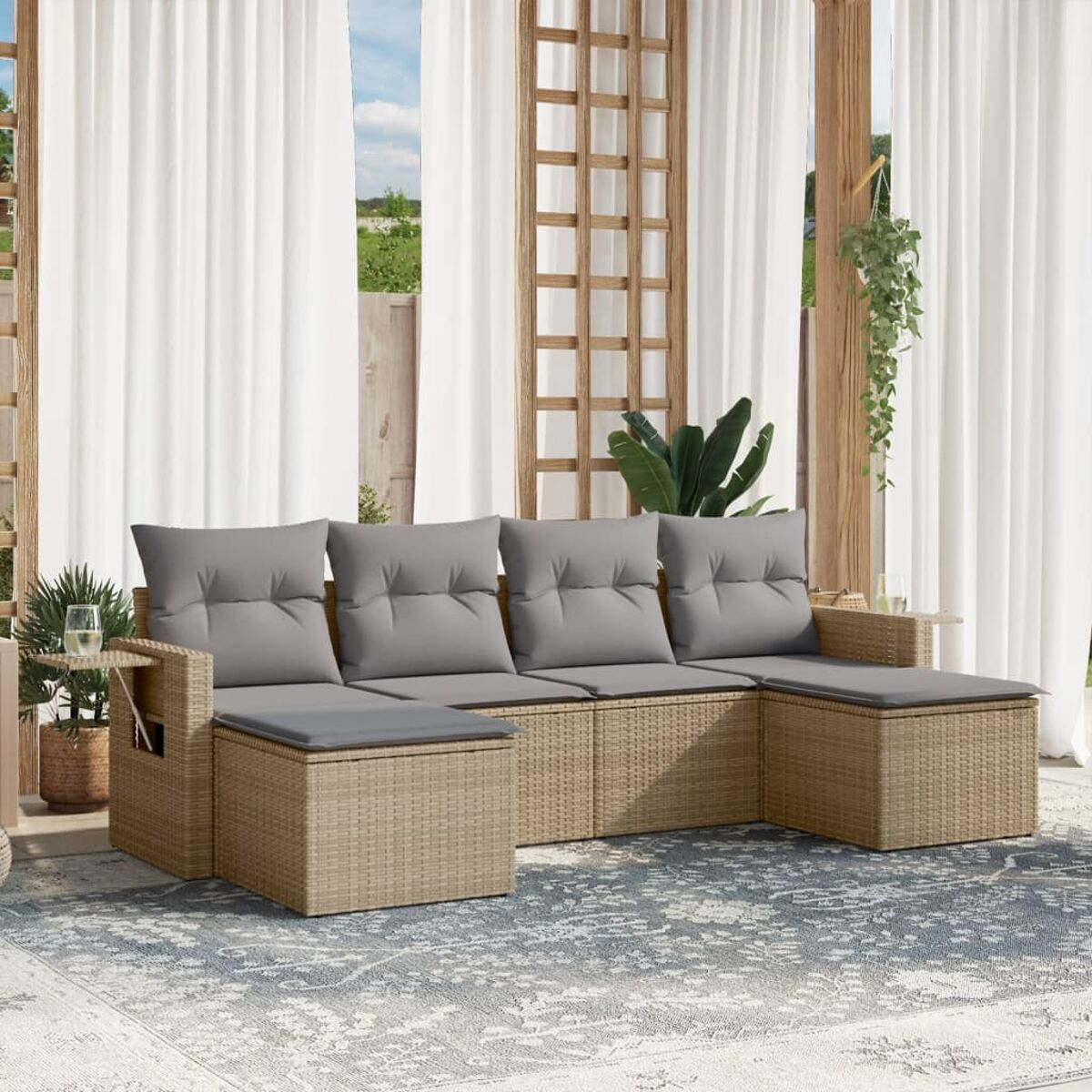 Geflochtenes Outdoor-Sofa-Set mit Kissen und Tisch. Hintergrund mit Vorhängen und Pflanzen.