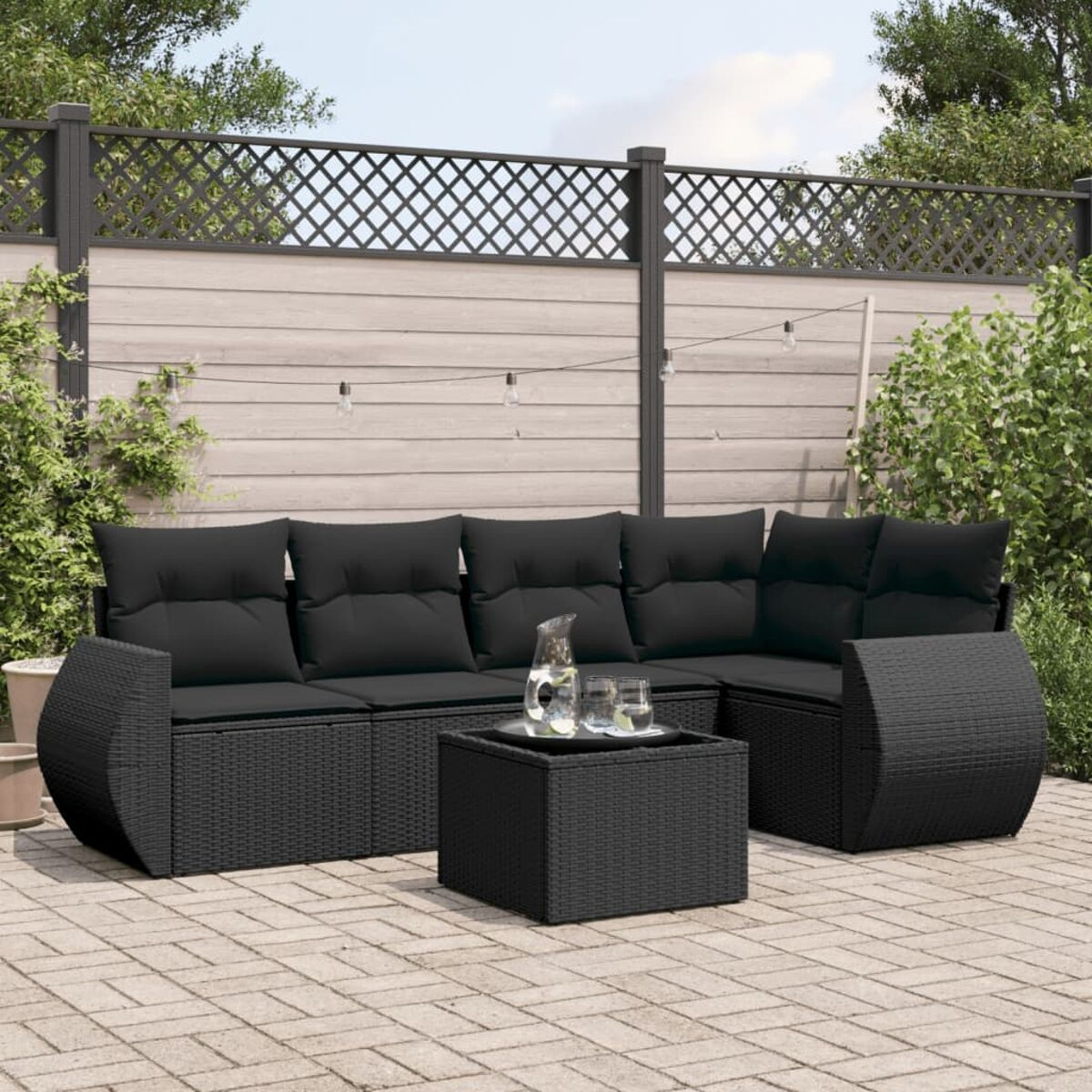 Schwarzes Outdoor-Set aus Korbgeflecht mit schwarzen Kissen und Couchtisch.