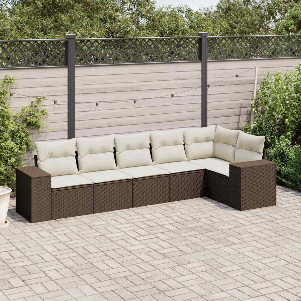 Set di mobili da esterno in vimini marrone con cuscini color crema. Include divano e angolo. Ambientazione patio.