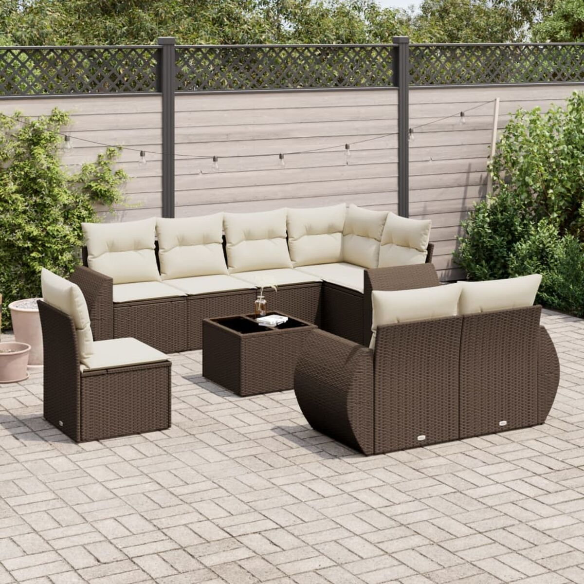 Set da patio marrone con cuscini color crema su un patio. Lo sfondo include un tavolo.