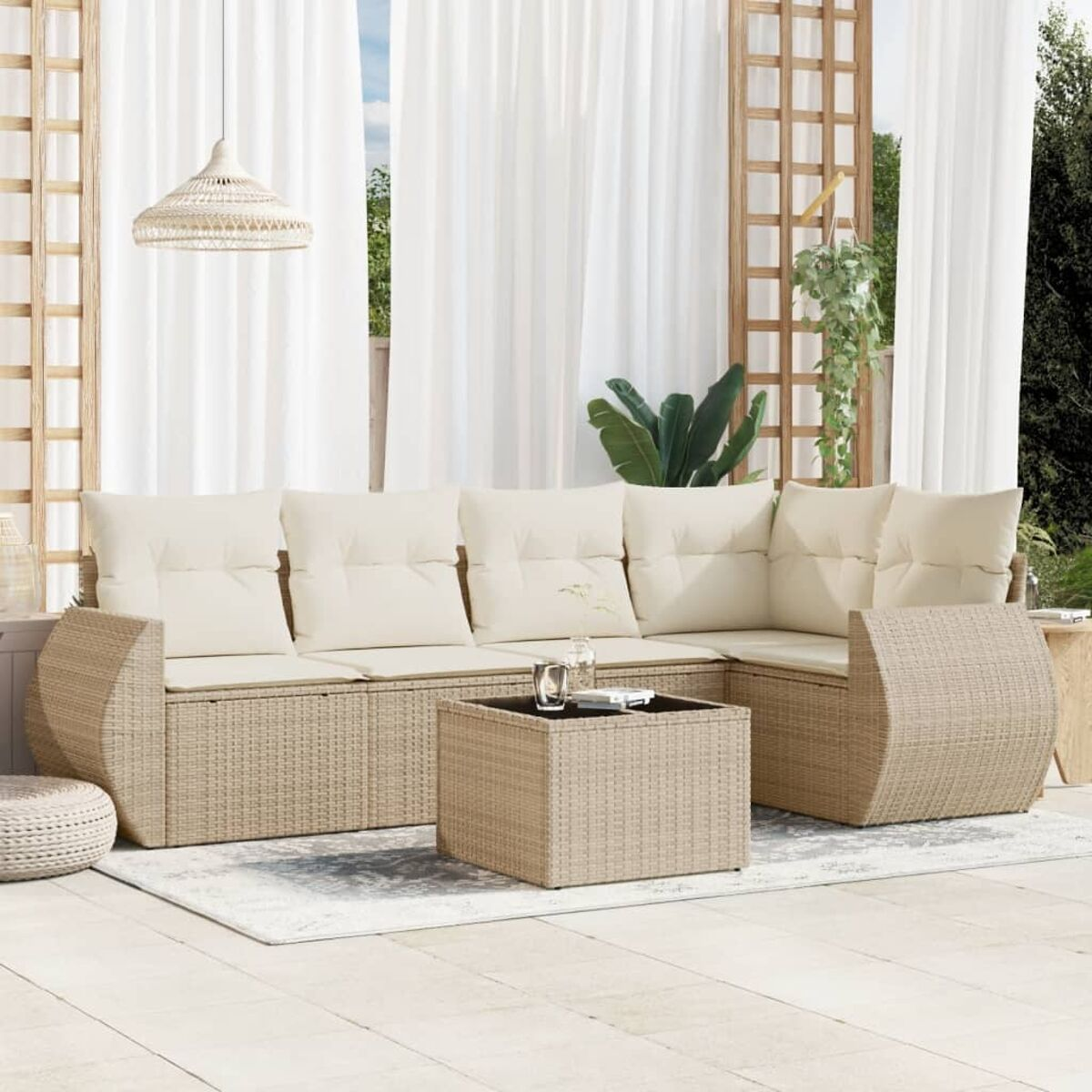 Beiges Rattansofa mit cremefarbenen Kissen, Couchtisch und Außenbereich.
