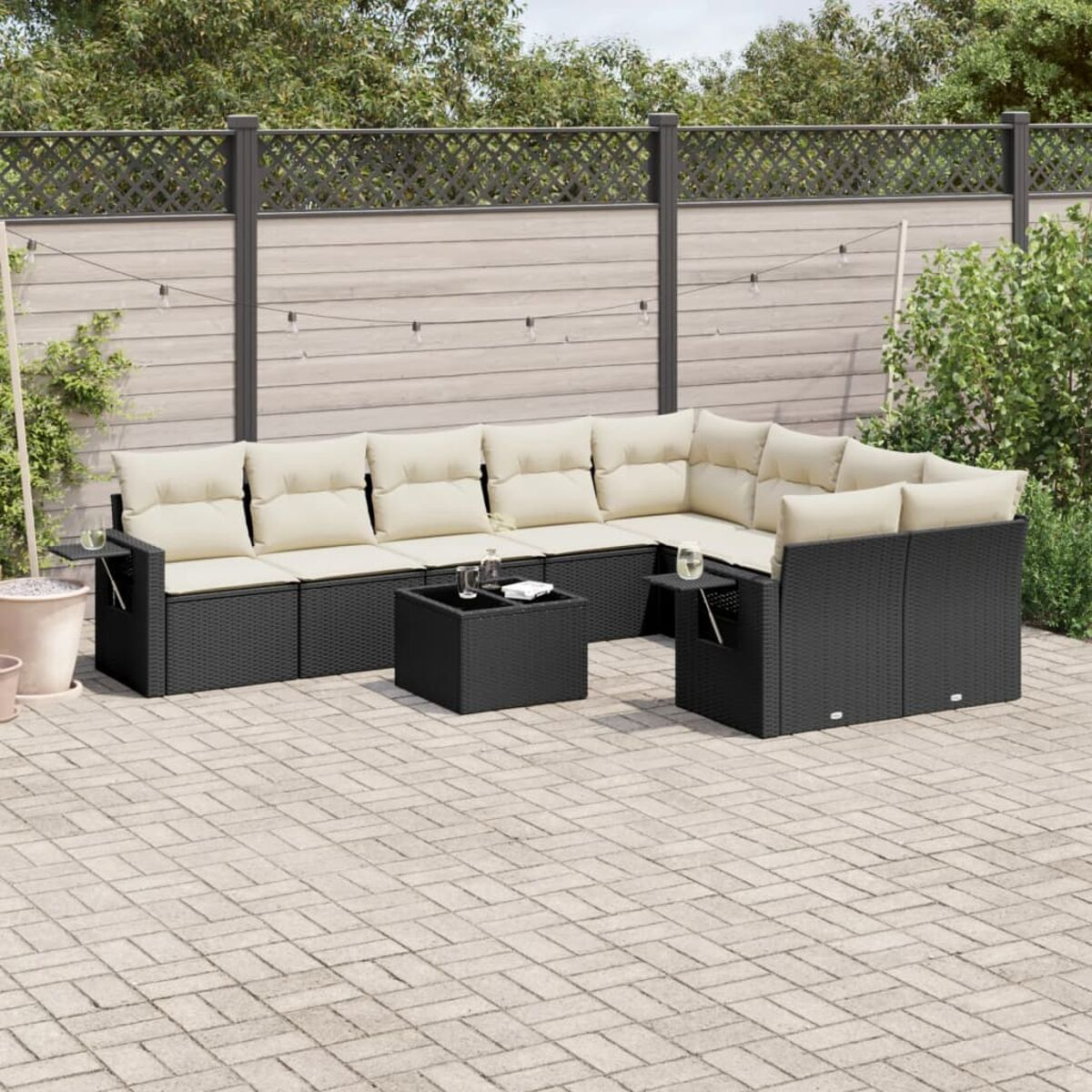 Outdoor-Set. Schwarzes Rattan-Sofa, Couchtisch und Stuhl. Beige Kissen. Stein-Terrasse.