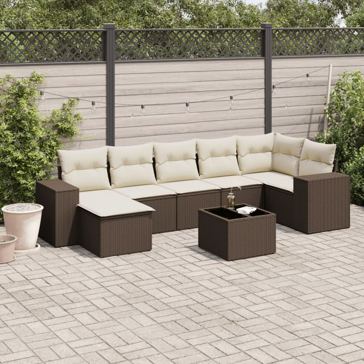 Divano componibile da esterno in rattan marrone con cuscini beige. Tavolino nero. Patio.