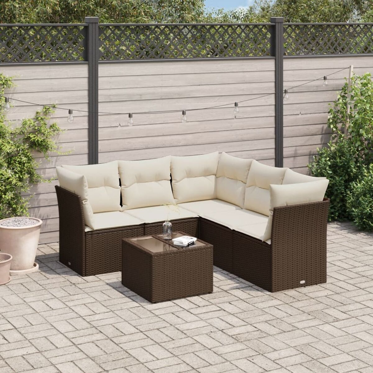 Set da esterno in vimini marrone su un patio pavimentato. Include divano, tavolo e cuscini.